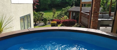 Una piscina con vistas a un jardín y una terraza de madera.