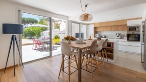 Een moderne keuken met houten kasten, een eethoek met een tafel en stoelen, en een groot raam met uitzicht op de omgeving.