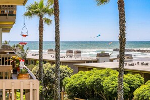 A coastal hotel with a view of the ocean, palm trees, and a beach.