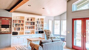 Uma sala de estar aconchegante com uma grande estante, um sofá confortável e um espaço de jantar com uma mesa.