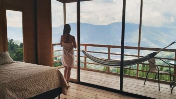 Un dormitorio con un ventanal grande, una hamaca y vistas a las montañas.
