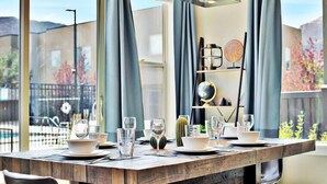 A dining table set with glasses, bowls, and a cactus centerpiece, with a view of a fence and trees outside. - Entrada at Moab 619 and 623 | Townies | Pool/Spa | Garage | Same Day Booking (Moab)