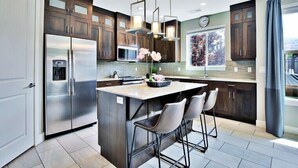 A modern kitchen with dark wood cabinets, stainless steel appliances, and a central island with bar stools. - Entrada at Moab 619 and 623 | Townies | Pool/Spa | Garage | Same Day Booking (Moab)