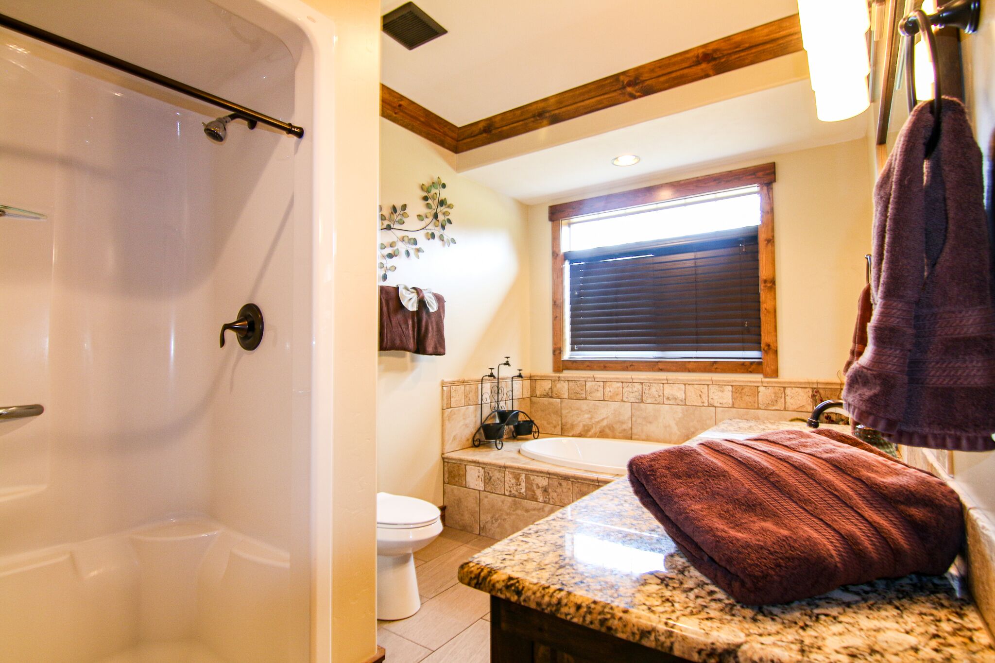 Une salle de bain équipée d’une douche, de toilettes, d’une baignoire et d’un comptoir en granit.