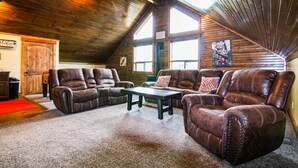 A spacious loft-style room with high ceilings and wooden beams, furnished with leather recliners and a central coffee table. - Luxury Cabin,Golf Course,Yellowstone, Stunning Mountain Views,Tubing, Rafting, (Island Park)