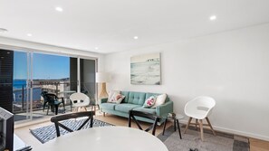 Relax in this stylish living room with a sofa, round table, and chair, plus a balcony with a glass door.