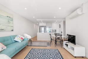 A modern apartment with a living room, dining area, and kitchenette.