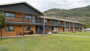 Un motel de varios pisos con balcones, mobiliario exterior y un césped.