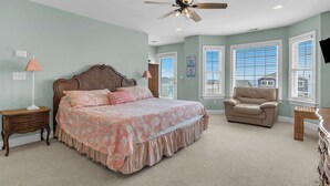 Ein Schlafzimmer mit Bett, Stuhl, Nachttisch, Lampe und Deckenventilator.