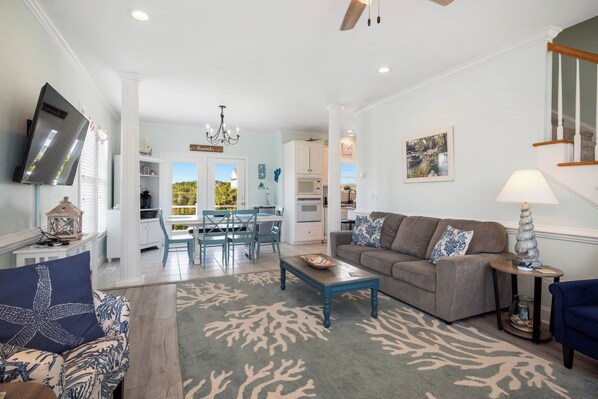 A spacious living room with a grey sofa, a coffee table, and a dining area with a table and chairs.