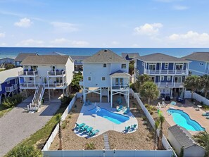 Zona residencial costera con varias casas, una piscina y vistas al océano.