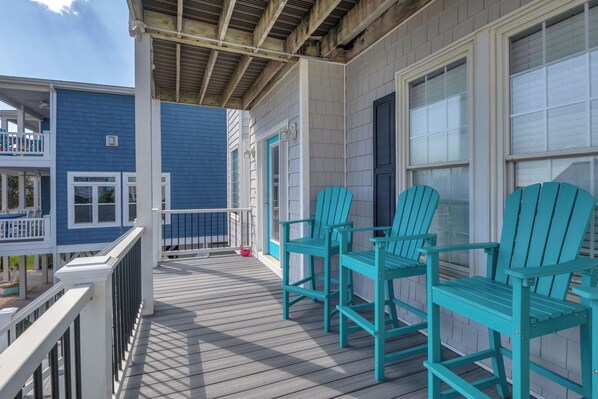 A covered porch with wooden railings and a set of turquoise Adirondack chairs. - 5 Buoys: Ocean View House Near Ocean Crest Pier (Oak Island)