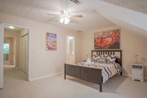 Ein Schlafzimmer mit einem Bett, einem Nachttisch, einem Deckenventilator und einem Poster an der Wand.