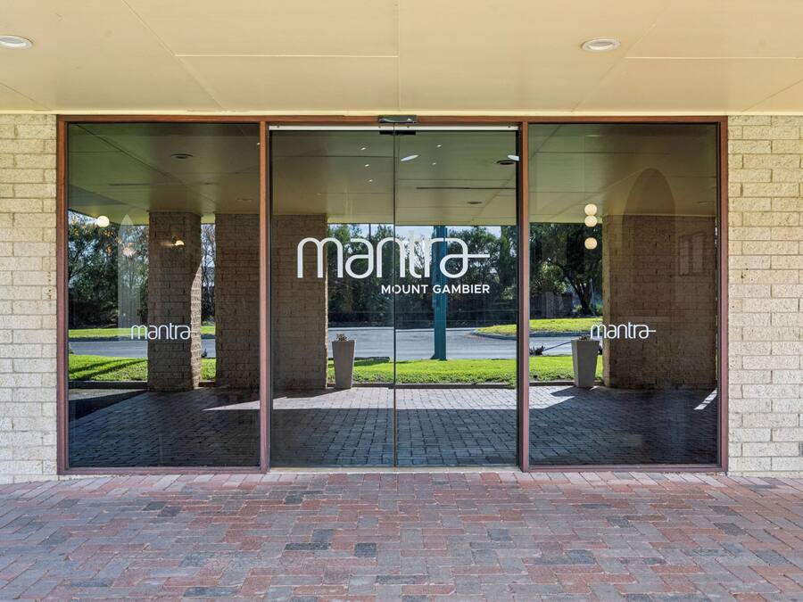 Entrada de un edificio con puerta de vidrio que muestra los nombres 'mantra' y 'MOUNT GAMBIER'.