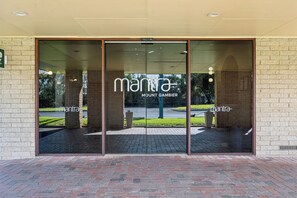 Entrada de un edificio con puerta de vidrio que muestra los nombres 'mantra' y 'MOUNT GAMBIER'.