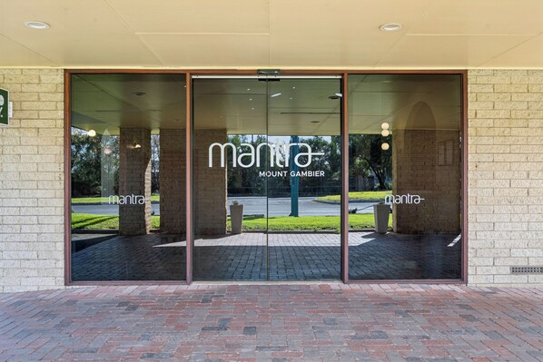 Entrada de un edificio con puerta de vidrio que muestra los nombres 'mantra' y 'MOUNT GAMBIER'.