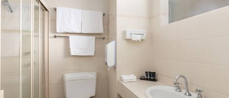 A bathroom with a toilet, sink, and glass shower enclosure.