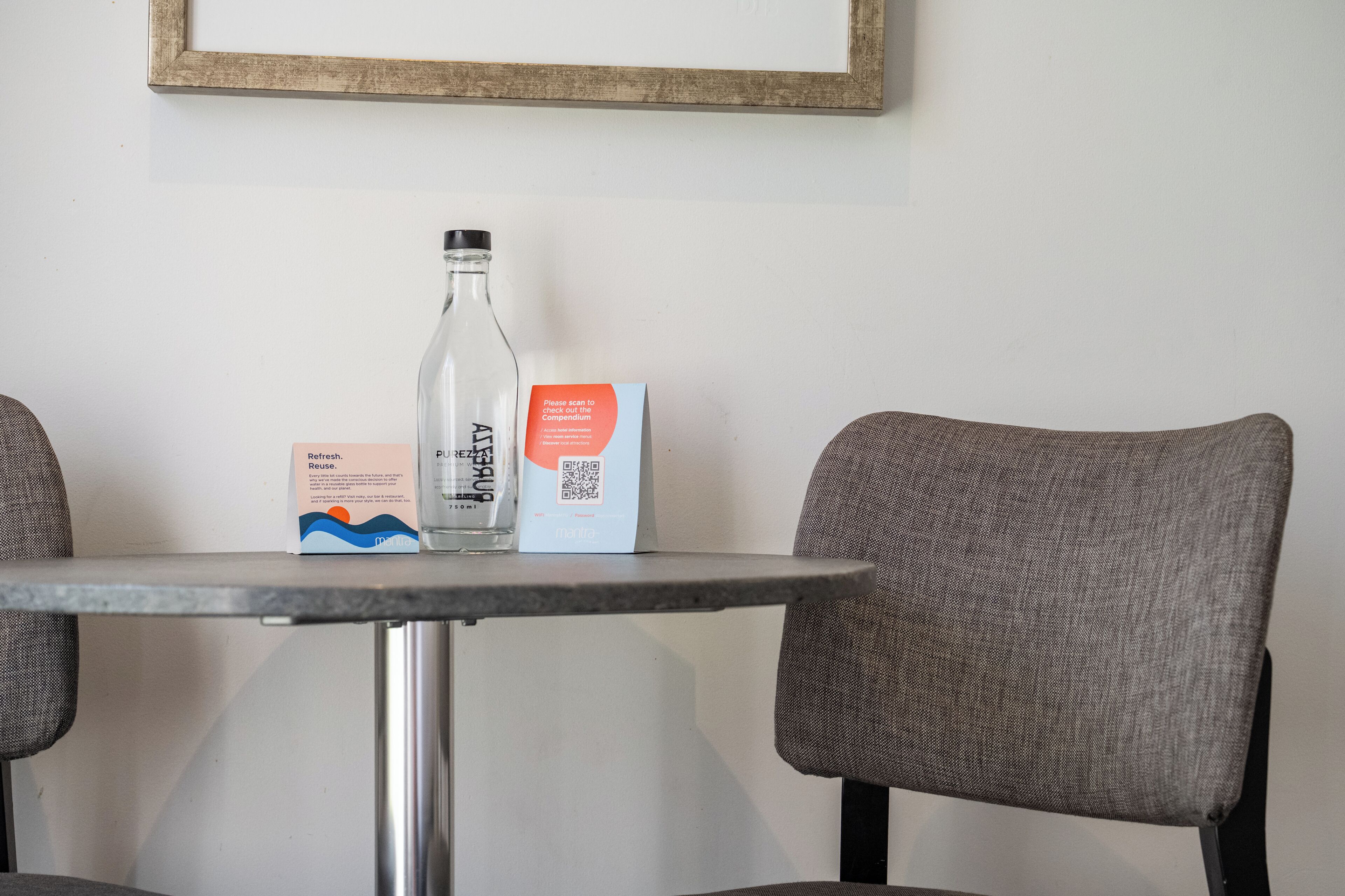 A table with a glass bottle, a QR code card, and a printed card with text.