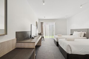 A hotel room with a bed, a desk, and a chair.