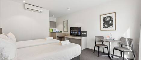 A hotel room with a bed, a desk, a chair, and a small table.