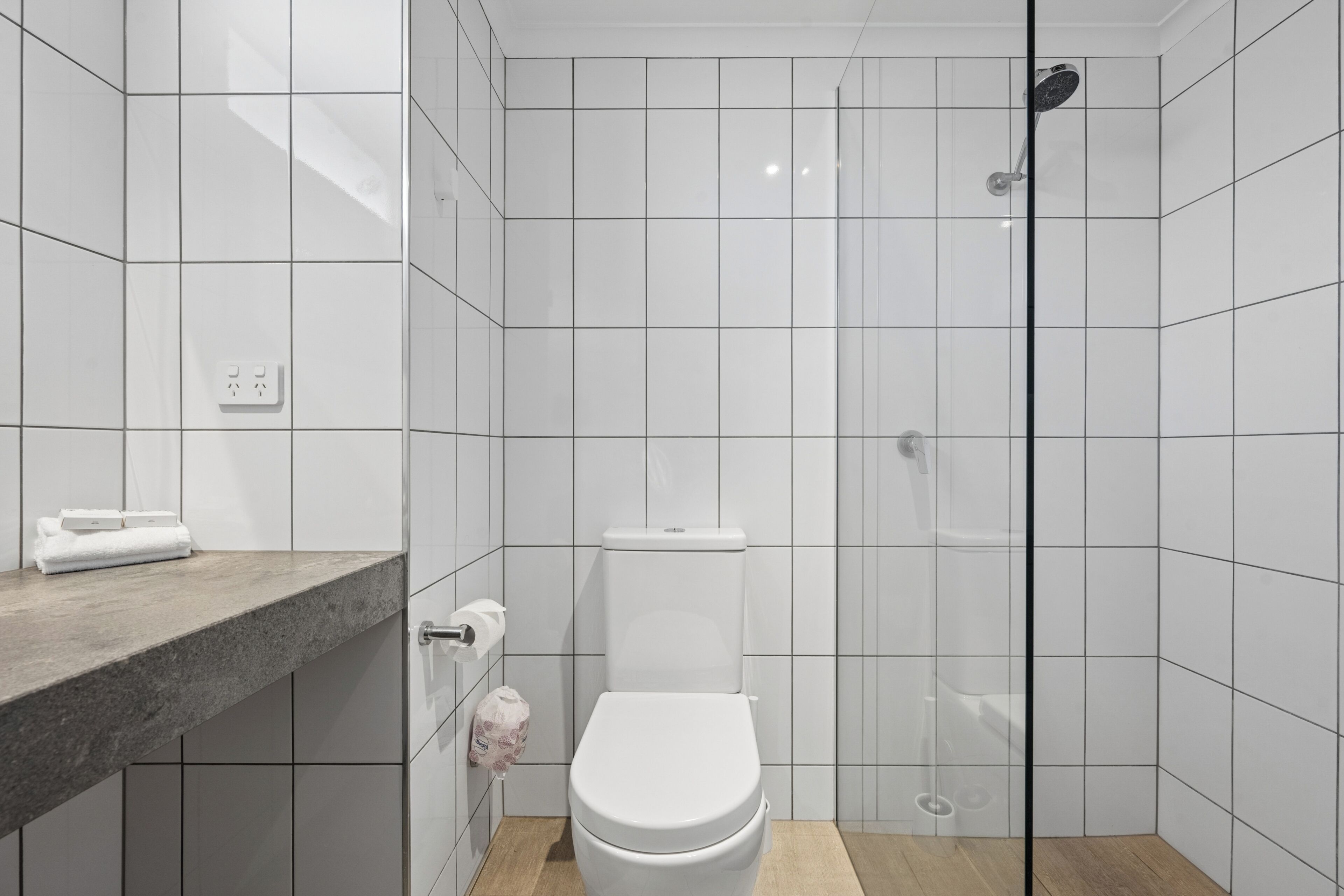 Een moderne badkamer met toilet, douche en wastafel met handdoek.