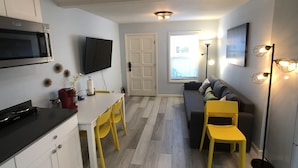 A compact living space with a kitchenette, a dining area, and a seating area with a sofa and chairs.