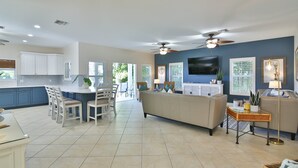 A spacious living area with a sofa, a dining table with chairs, and a kitchen area with cabinets and a TV. - Luxury waterfront home with a heated pool and spa! (Anna Maria)