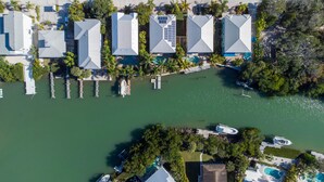 An aerial view of a resort with multiple buildings, a marina, and a large body of water. - Luxury waterfront home with a heated pool and spa! (Anna Maria)