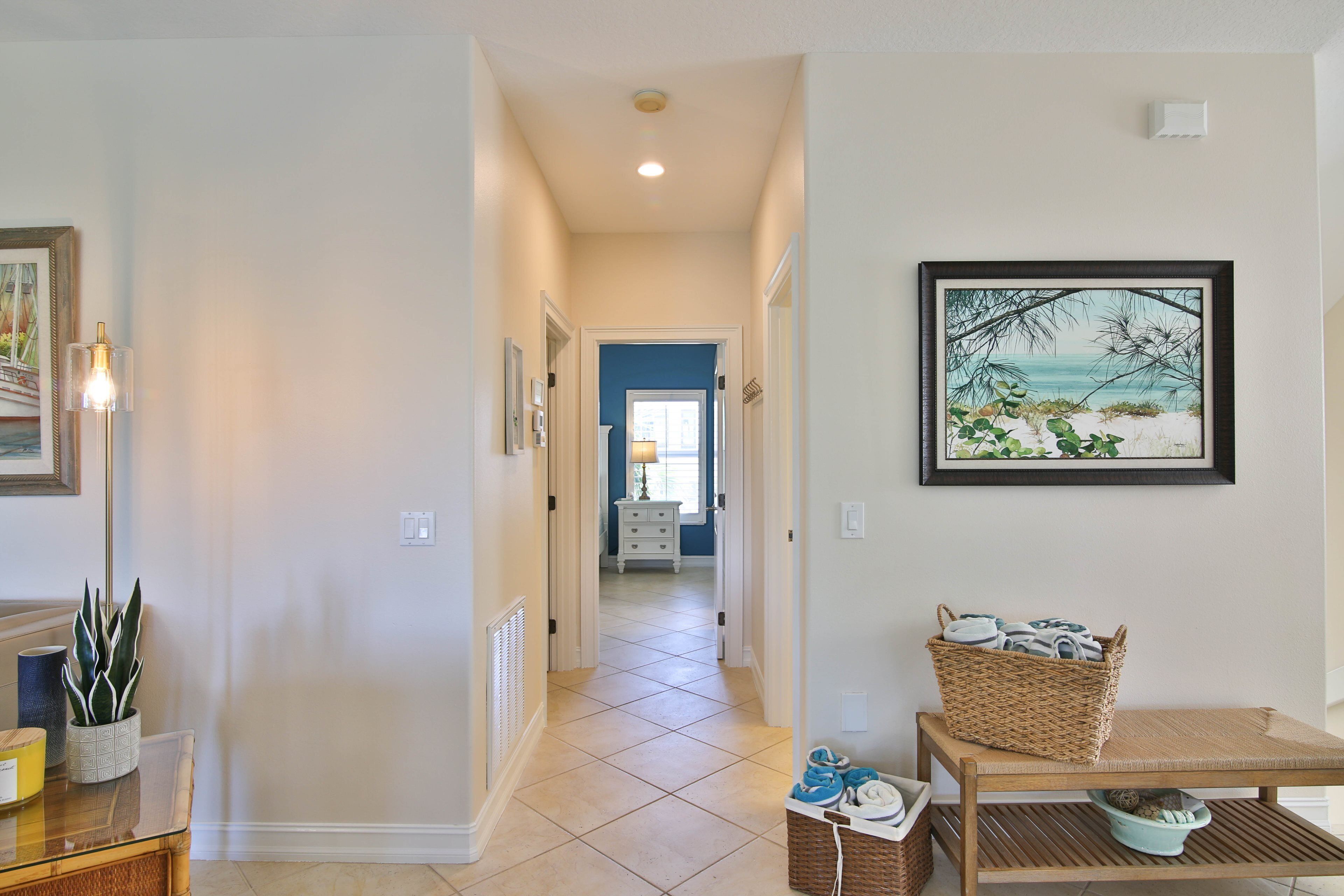 A hallway with a framed painting, a wicker basket, and a table with shoes.