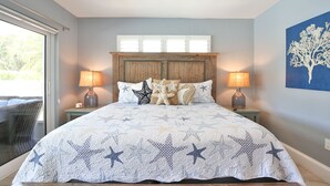 A bedroom with a bed, two bedside lamps, a wooden headboard, and a large window. - 3 bedroom 2 bathroom canal front home with a heated pool located in Anna Maria (Anna Maria Island)