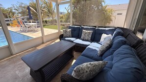 A covered outdoor seating area with a pool, wicker furniture, and a view of the backyard. - 3 bedroom 2 bathroom canal front home with a heated pool located in Anna Maria (Anna Maria Island)