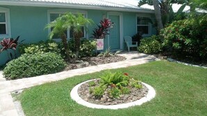 A house with a well-maintained lawn, a circular flower bed, and various tropical plants. - Delightful, comfortable villa just steps from the beach! (Holmes Beach)