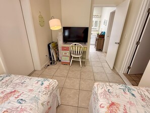 A hotel room with two beds, a desk with a TV, a chair, and a lamp. - Delightful, comfortable villa just steps from the beach! (Holmes Beach)
