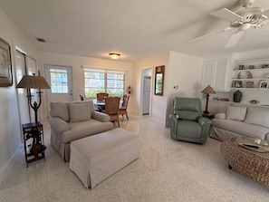 A spacious living room with a dining area, a kitchenette, and a ceiling fan.