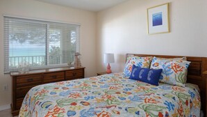 A bedroom with a bed, a dresser, a window with blinds, a lamp, and a framed picture on the wall.