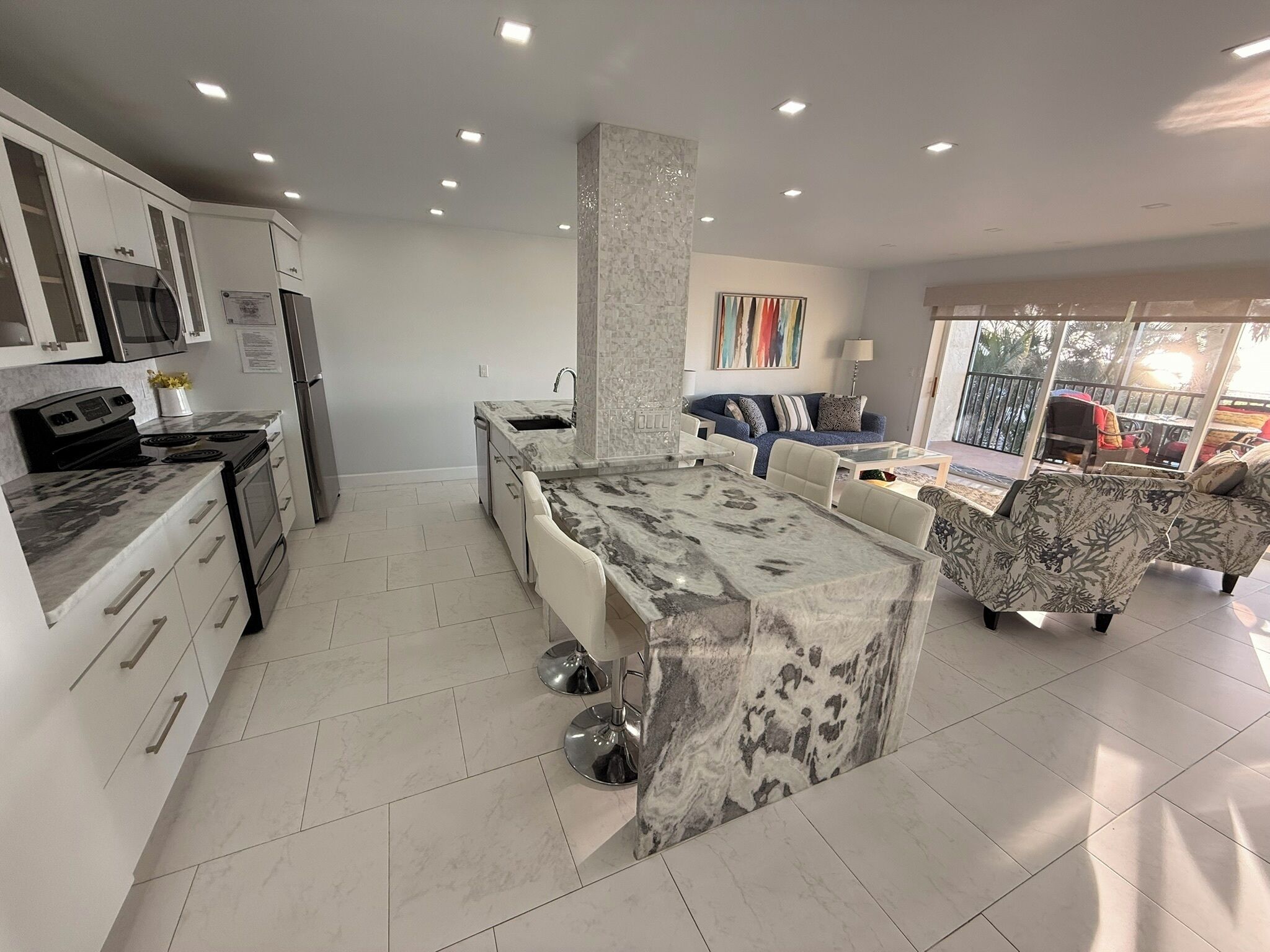 A modern kitchen with a central island, built-in appliances, and a dining area with a sofa and table.