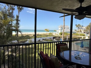 A balcony with a view of the beach, a pool, and a house in the background. - Gulf-front, heated pool, stocked kitchen, and private parking! (Holmes Beach)