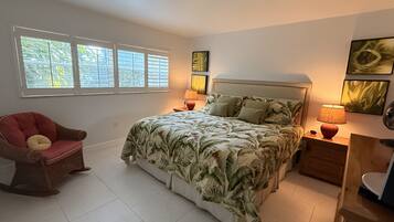 Une chambre à coucher avec un lit, une chaise, une table de chevet et une lampe.