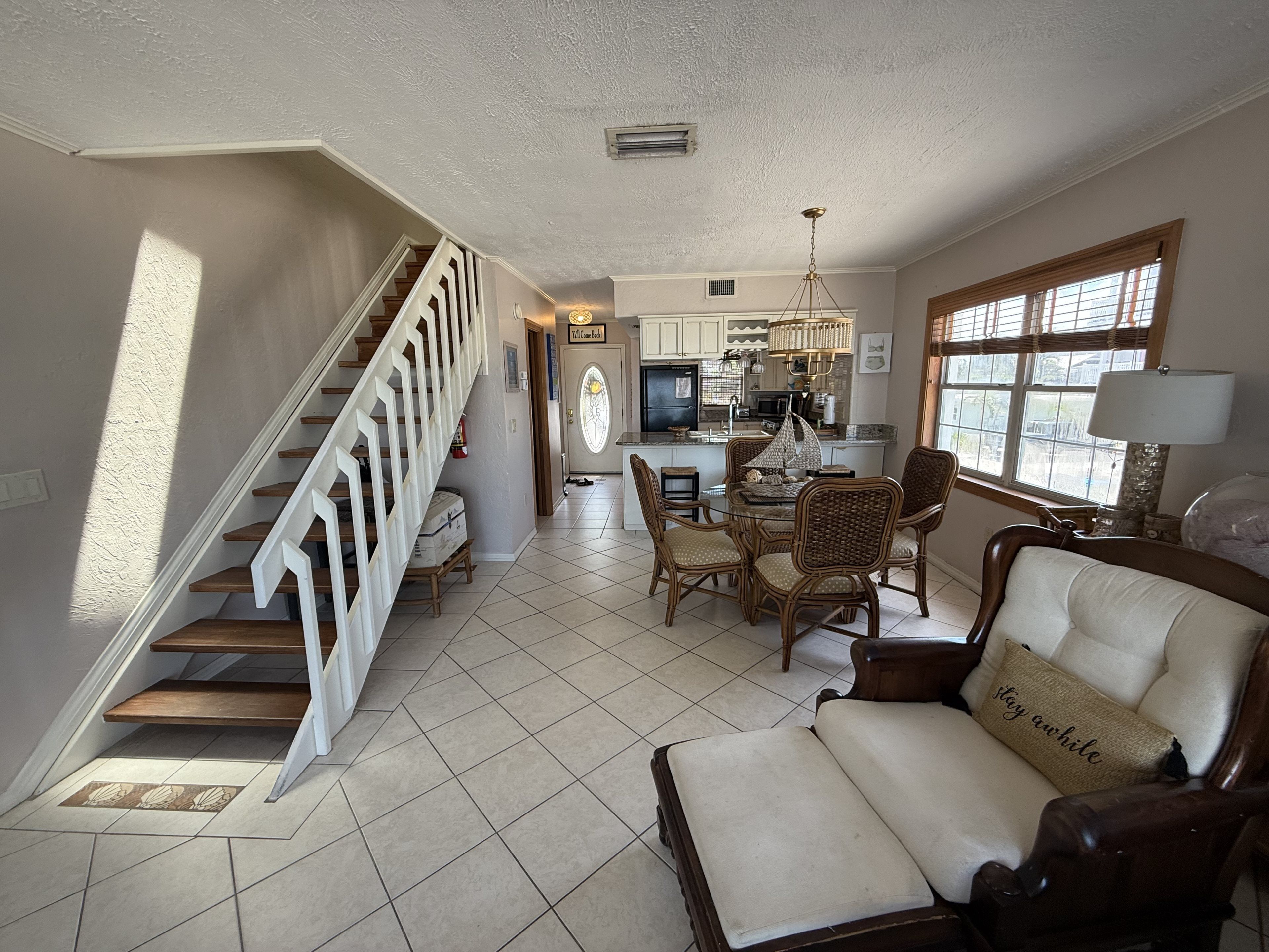 A spacious living area with a staircase, dining table, and comfortable seating.