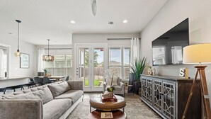 A modern living room with a sofa, coffee table, and a cabinet with a TV. - Stay at Steph’s Farmhouse! Right next to Kalahari Resorts and Dell Diamond! (Round Rock)