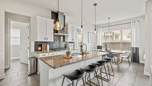A modern kitchen with white cabinets, granite countertops, and bar stools. - Stay at Steph’s Farmhouse! Right next to Kalahari Resorts and Dell Diamond! (Round Rock)