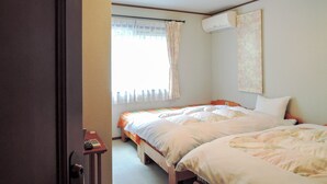 A bedroom with two beds, a window with curtains, a ceiling light fixture, and a wall-mounted air conditioner.