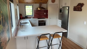 Eine moderne Küche mit einer zentralen Kochinsel, weißen Schränken, einem Edelstahl-Kühlschrank und einer roten Backsteinwand.