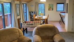 Ein gemütliches Wohnzimmer mit Holzboden, einem Kicker und zwei bequemen Sesseln.