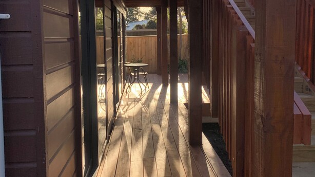 Eine überdachte Holzterrasse mit einer Treppe zu einer erhöhten Ebene.