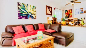 A living room with a brown leather sofa, red cushions, a wooden coffee table, and various decorative items. - Stunning private Comfort villa with pool in Playacar walk to the beach (Playa del Carmen)