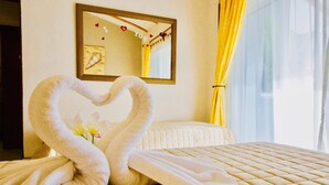 A hotel room with a bed, a heart-shaped towel arrangement, a mirror, and a window with curtains. - Stunning private Comfort villa with pool in Playacar walk to the beach (Playa del Carmen)