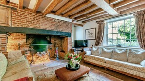 Una sala de estar acogedora con chimenea de ladrillo, un sofá y un televisor.