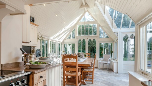 Una cocina amplia con una gran mesa de comedor, armarios de madera y una estufa empotrada.