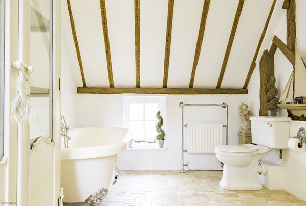 A bathroom with a bathtub, toilet, and a window with a potted plant.